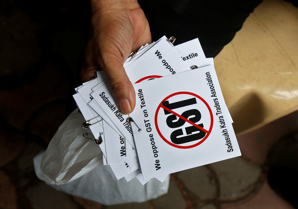 A cloth merchant holds message papers to distribute as he attends a procession during a strike to protest the implementation of the Goods and Services Tax (GST) on textiles in Kolkata, India June 30, 2017.  (Reuters Photo/Rupak De Chowdhuri)
