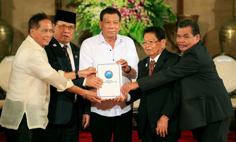 Philippine President Rodrigo Duterte, center, with Moro Islamic Liberation Front chairman Al Haj Murad Ebrahim, second from the left, during a ceremony at the Malacanang presidential palace in Manila, Philippines on Monday (17/07).  (Reuters Photo/Romeo Ranoco)