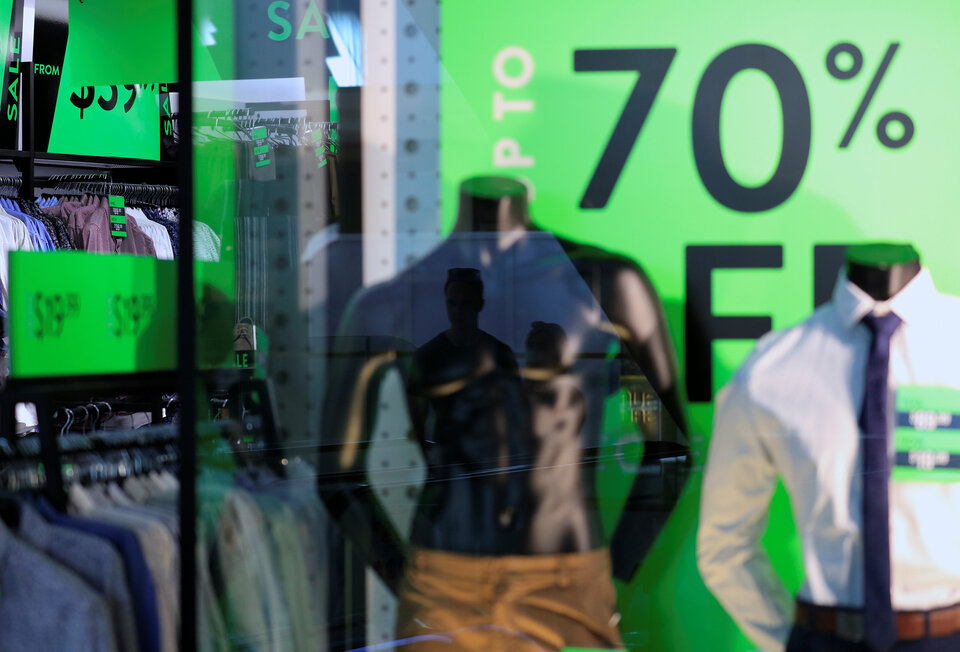 Shoppers reflected in the window of a retail store displaying sales signs in central Sydney, Australia. (Reuters Photo/Steven Saphore)