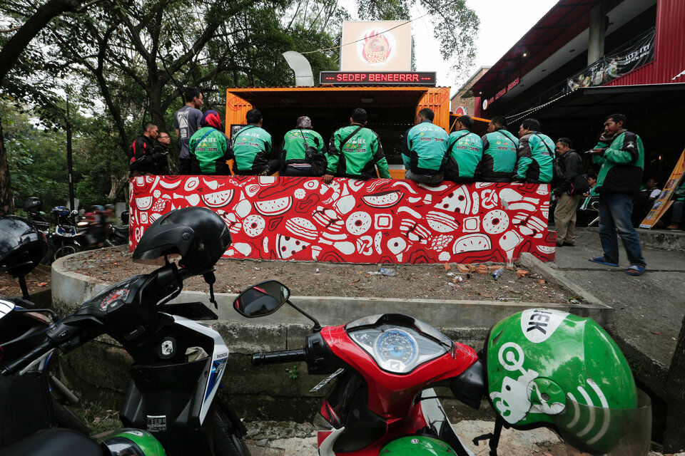 Go-Jek drivers sit as they wait for their orders at a food stall in Jakarta, Indonesia, July 13, 2017. (Reuters Photo/Beawiharta)