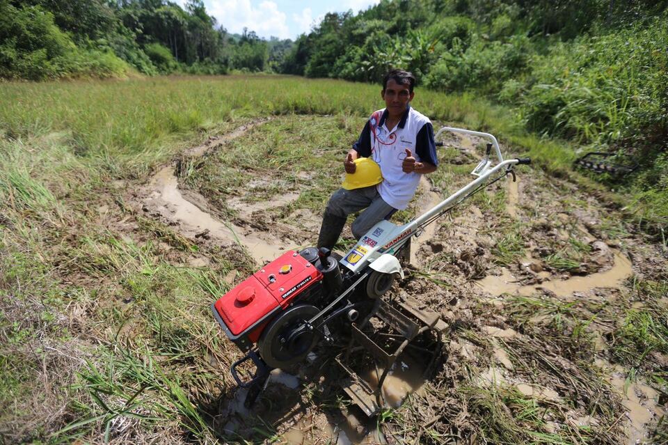 A farmer using the hand tractor to plow the rice paddies in West Kalimantan. (Photo from PT Finnantara Intiga)