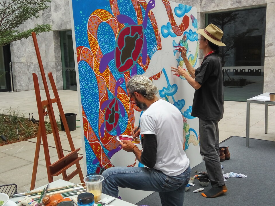 Australian indigenous painter Jandamarra Cadd, left, and Indonesian painter Jerry Thung working on their joint artwork in the courtyard of the Australian Embassy in Jakarta on Tuesday (11/07). (JG Photo/Dhania Putri Sarahtika)