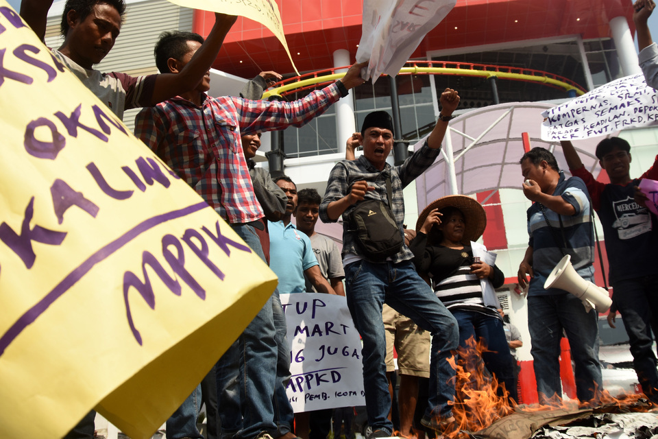 Members of the Community Care for Depok City Development, or MPPKD, burn posters at a rally in front of a Transmart supermarket in Depok, West Java, on Tuesday (04/07). Protesters demanded the closure of the Depok Transmart, claiming the supermarket threatens the livelihoods of traditional traders in the area. (Antara Photo/Indrianto Eko Suwarso)



