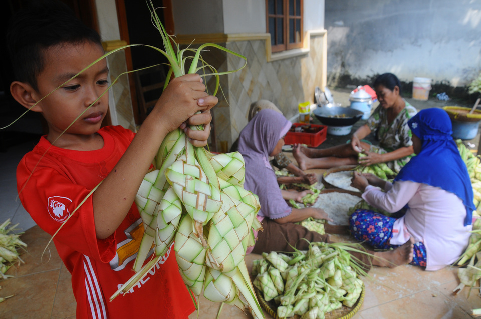 A boy hangs ketupat, rice cakes wrapped in coconut leaves, in Klaten, Central Java, on Saturday (01/07) as part of 'Lebaran Ketupat' celebrations, traditionally held seven days after Idul Fitri. (Antara Photo/Aloysius Jarot Nugroho)