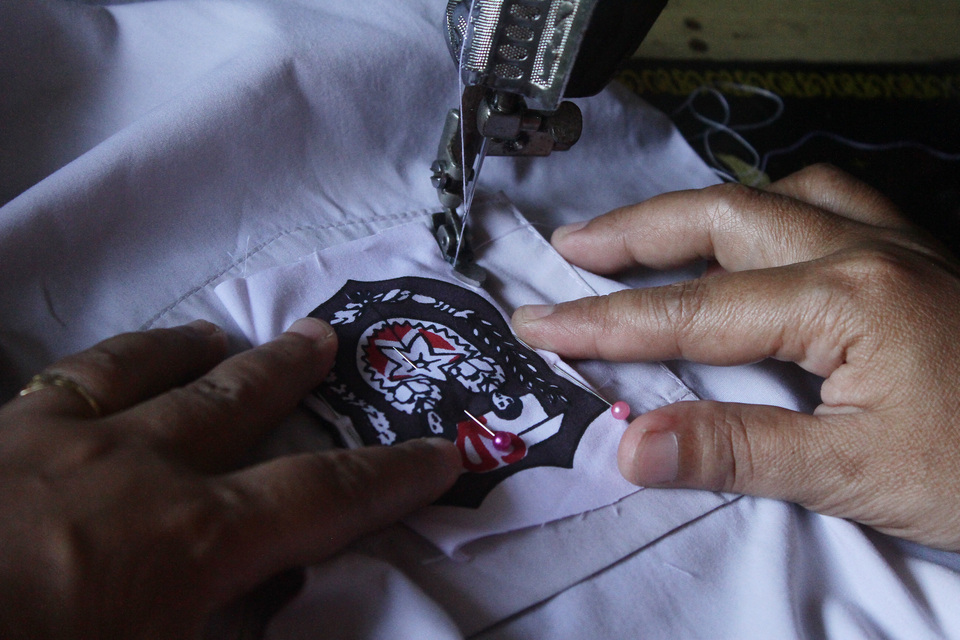 A tailor sews a badge on a school uniform in Malang, East Java, on Wednesday. (Antara Photo/Ari Bowo Sucipto)