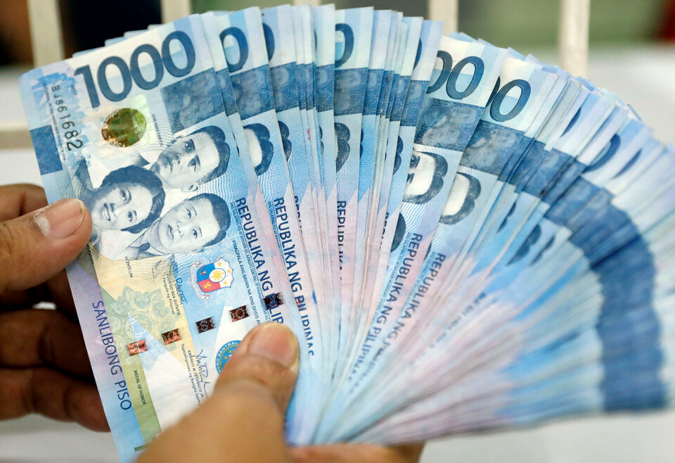 A worker shows Philippine peso bills inside a money changer in metro Manila, Philippines on Aug. 14, 2017. (Reuters Photo/Dondi Tawatao)