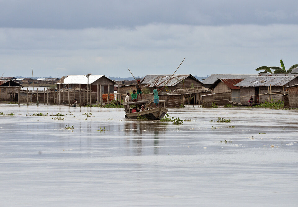 People row a boat in the flood waters next to their partially submerged huts in Morigaon district in the northeastern state of Assam, India, on Friday (18/08). (Reuters Photo/Anuwar Hazarika)