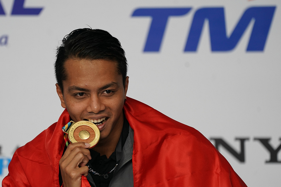 Indonesian swimmer I Gede Siman Sudartawa poses with the gold medal in his hand. (Antara Photo/Sigid Kurniawan)