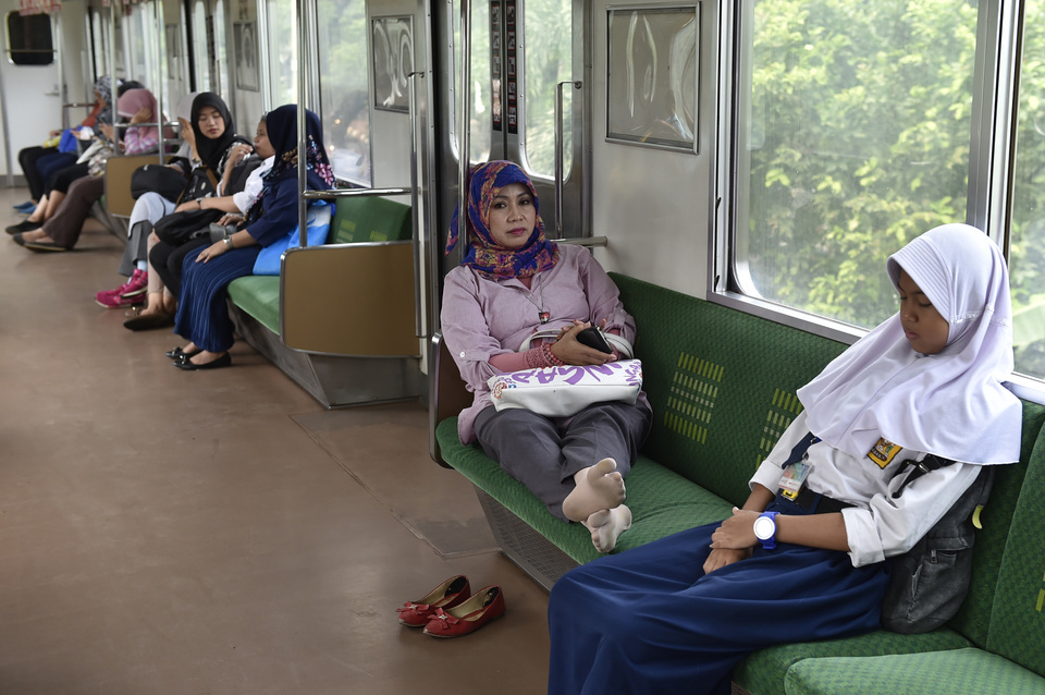 A passenger stretches her legs on a commuter line train in Jakarta on Tuesday (15/08). The operator has been urging passengers to be civil and mindful of others while using public facilities. (Antara Photo/Puspa Perwitasari)