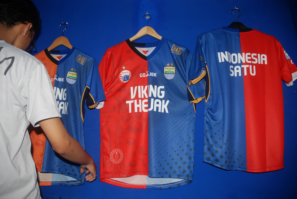 A man is pictured hanging jerseys on display that reads 'VIKING THEJAK' on the front and 'Indonesia Satu' ('Indonesia One') on the back, at the official Persib Bandung store in West Java on Thursday (03/08). The store has begun to produce and sell jerseys combining Persib Bandung and Persija Jakarta team jerseys in an effort to show unity following the brutal murder of Rico Andrian. On July 22, Rico was attacked by fellow Persib supporters during a Liga 1 match between two arch-enemies, Persija Jakarta and Persib Bandung. (Antara Photo/Fahrul Jayadiputra)