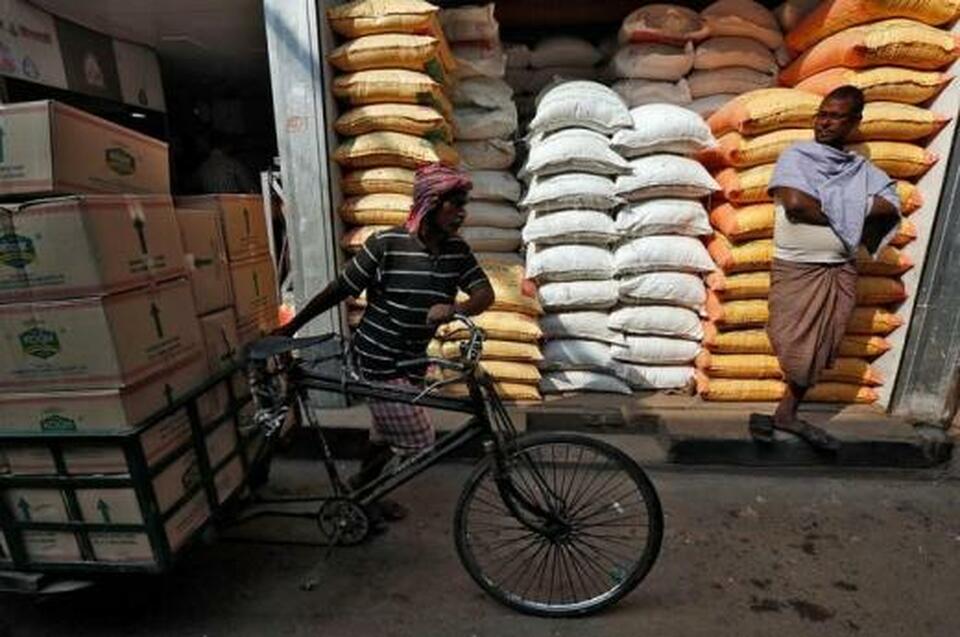 A laborer carries vegetable oil packets on a tricycle as a man stands in front of his shop selling food grains, at a wholesale market in Kolkata, India, January 4, 2017. (Reuters Photo/Rupak De Chowdhuri)