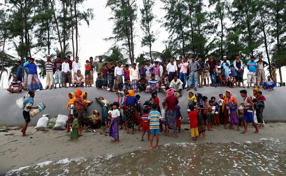 Local residents watch as Rohingya refugees arrive on the shore after crossing the Bangladesh-Myanmar border by boat through the Bay of Bengal in Teknaf, Bangladesh, on Thursday (07/09). (Reuters Photo/Danish Siddiqui)