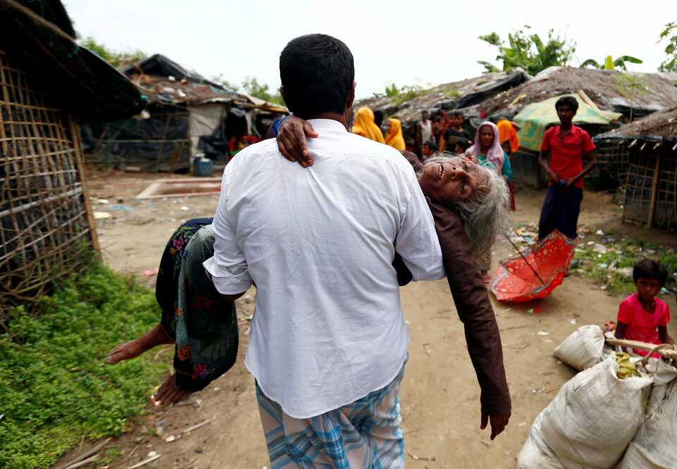 A man carries a Rohingya refugee woman from the shore after she crossed the Bangladesh-Myanmar border by boat through the Bay of Bengal in Teknaf, Bangladesh, Thursday (07/09). (Reuters Photo/Danish Siddiqui)
