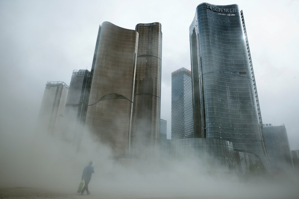 A man walks through a cloud of dust whipped up by wind at the construction site near newly erected office skyscrapers in Beijing, China April 20, 2017. (Reuters Photo/Thomas Peter)