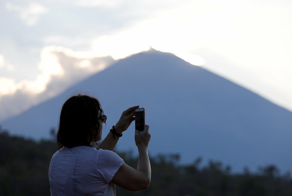 A tourist takes a picture of the sun set near Mount Agung, a volcano on the highest alert level, from Amed on the resort island of Bali, Indonesia September 26, 2017. (Reuters Photo/Darren Whiteside)