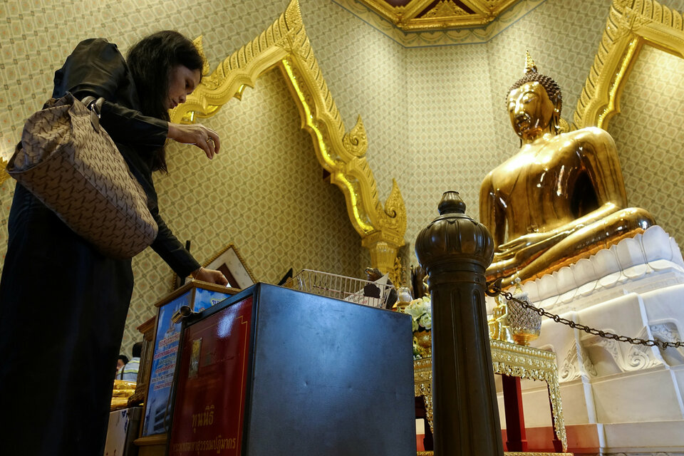 A woman donates her money into donation boxes at a temple in Bangkok on Oct. 18, 2017. (Reuters Photo/Athit Perawongmetha)