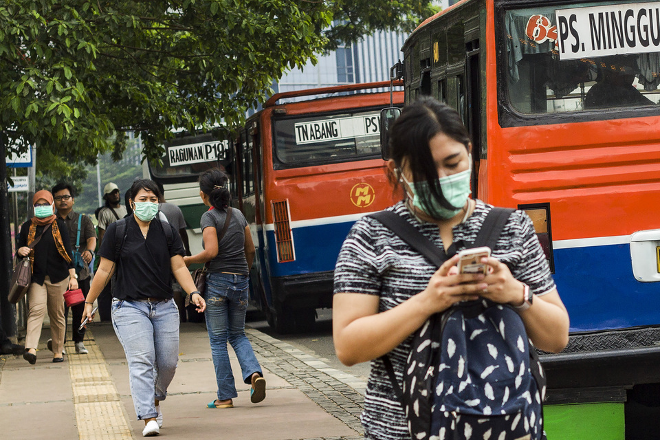 City residents wear masks to protect themselves from air pollution while crossing over a pedestrian bridge in Sarinah, Jakarta, on Monday (09/10). Based on data from the Air Pollution Standard Index, air quality in Jakarta often reaches unhealthy levels. (Antara Photo/Galih Pradipta)