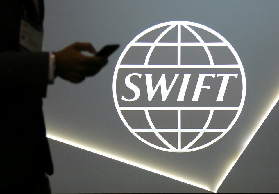 A man using a mobile phone passes the logo of global secure financial messaging services cooperative SWIFT at the SIBOS banking and financial conference in Toronto, Ontario, Canada October 19, 2017.  (Reuters Photo/Chris Helgren)