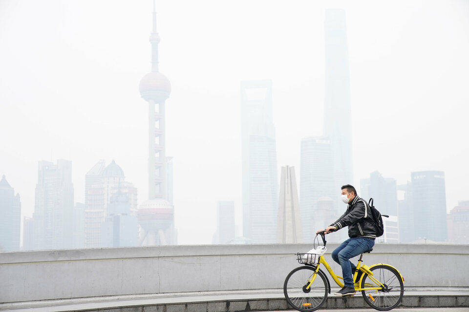 A man wearing a face mask rides a bicycle on a bridge in front of the financial district of Pudong covered in smog during a polluted day in Shanghai. (Reuters Photo/Aly Song)