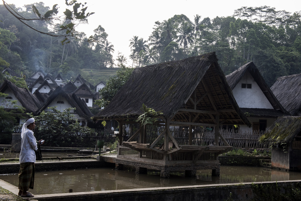 A resident stands among traditional houses in Kampung Naga, or Dragon Village, in Tasikmalaya district, West Java, on Thursday (02/11). Around 300 members of the Naga community live in the village, which consists of 113 buildings. Villagers still adhere to their original culture and wear traditional clothes during ceremonial rituals held to preserve the sacred forest, which they consider their life source. (Antara Photo/M Agung Rajasa)