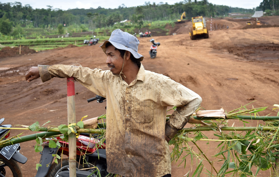 A resident appears in front of a barricade placed near the Salatiga-Kartasura toll road project in Susukan, Semarang, Central Java, on Tuesday (07/11). Residents have enacted a blockade on the project, demanding development manager Waskita Karya to withdraw a barrier fence that they say encroaches on private agricultural land. (Antara Photo/Aditya Pradana Putra)

