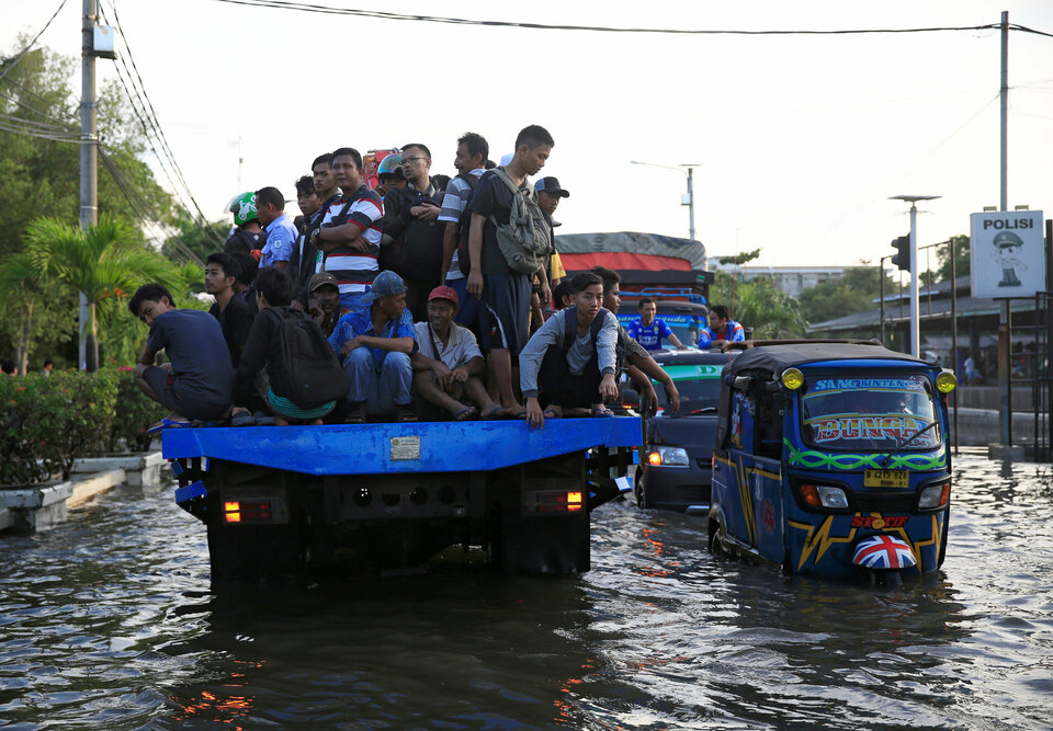 Workers being transported at the back of a truck on a flooded street after high tide hit Muara Baru area in Jakarta, Indonesia, December 6, 2017.  Reuters Photo/Beawiharta
