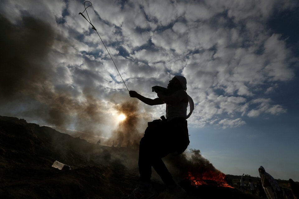 A Palestinian protester uses a sling to hurl stones towards Israeli troops during clashes near the border with Israel in the central Gaza Strip on Friday (08/12) as Palestinians call for a 'day of rage' in response to US President Donald Trump's recognition of Jerusalem as Israel's capital. (Reuters Photo/Ibraheem Abu Mustafa)