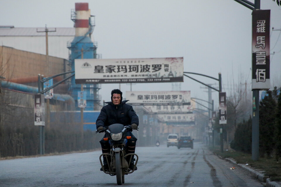 A man rides a motobike past a ceramics factory in rural Gaoyi county near Shijiazhuang, Hebei province, China, on Dec. 6, 2017. (Reuters Photo/Thomas Peter)