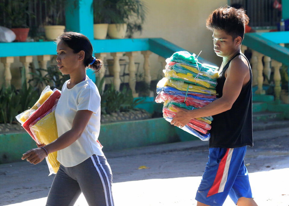 Displaced Filipinos staying at an evacuation center after Mount Mayon volcano spewed lava and other material carry their relief items in Legazpi city, Albay province, Philippines, on Jan. 26, 2018. (Reuters Photo/Romeo Ranoco)