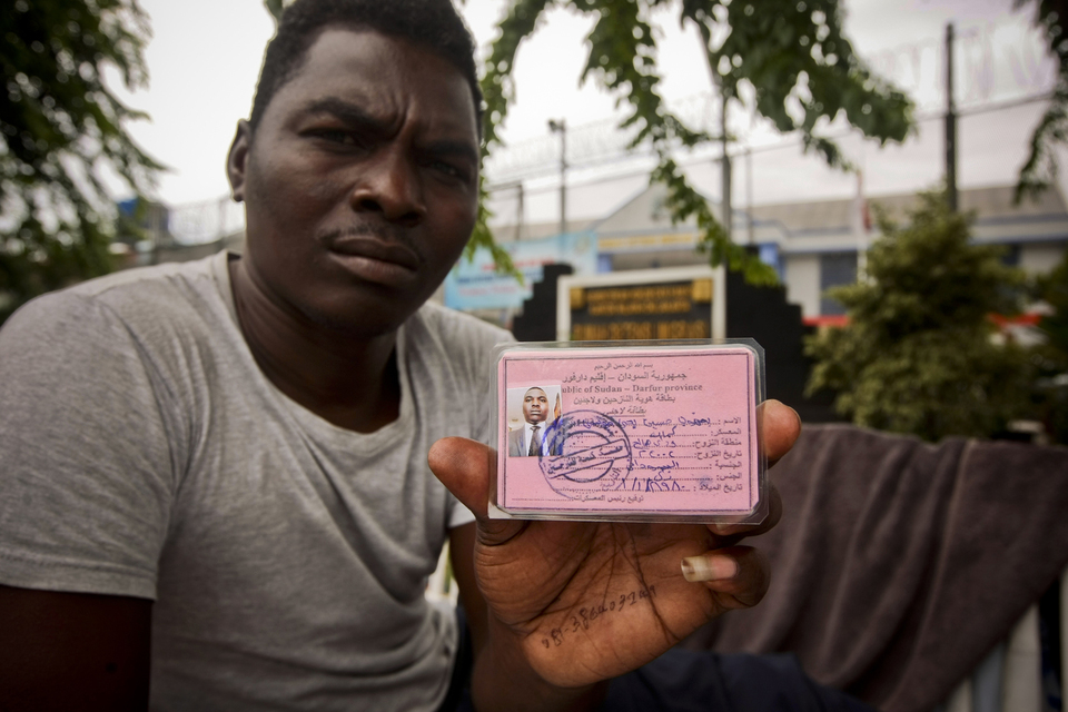 A Sudanese man shows his identity card while sitting on the pavement in front of the Jakarta Immigration Detention Center in Kalideres, West Jakarta, on Friday (05/01). (JG Photo/Yudha Baskoro)
