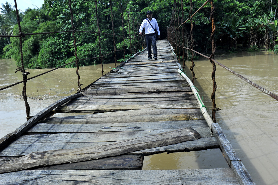 A man crosses a perilous wooden bridge in Babakan Cimarga, Lebak, Banten, on Wednesday (31/01). The local government says it has difficulty in maintaining the district's 1,200 bridges due to budget constraints and no support from the central government and private sector. (Antara Photo/Asep Fathulrahman)