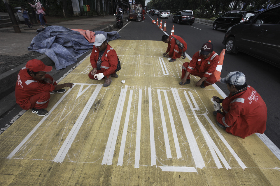 Workers paint a motorcyle lane on Jalan Medan Merdeka in Central Jakarta on Monday (15/01). (Antara Photo/Muhammad Adimaja)