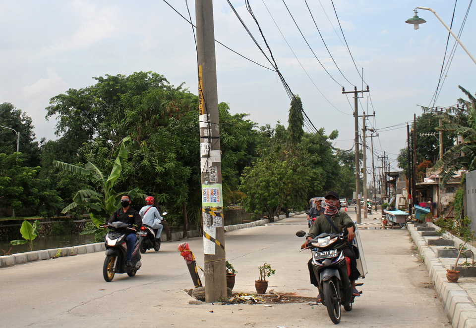 Power poles remain in the middle of a newly built road in Bekasi, West Java, on Wednesday (24/01). (Antara Photo/Risky Andrianto)