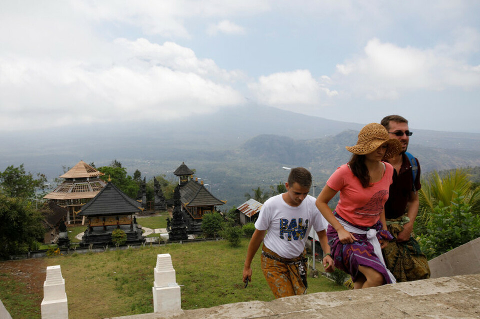 Tourists walk up the stairs at Penataran Agung Lempuyang Temple with Mount Agung, on its highest alert level, in the background in Karangasem, Bali, on Sept. 25, 2017. (Reuters Photo/Darren Whiteside)