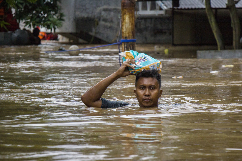 A Jakarta resident calmly tries to reach dry land after a big flood sweeps through Pasar Minggu in the south of the capital on Monday (05/02). (Antara Photo/Galih Pradipta)
