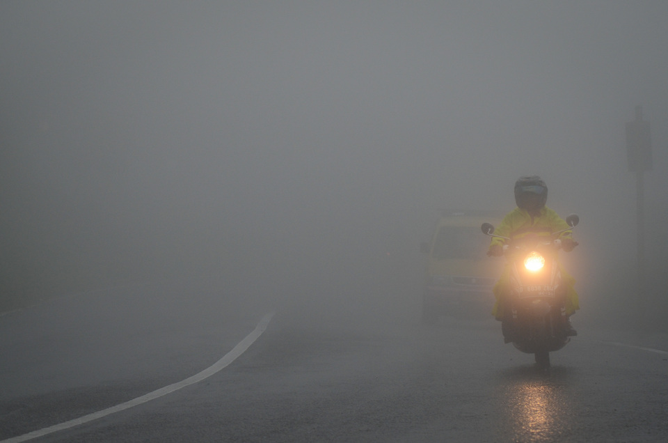 A motorcyclist drives on a road laden with fog in Bogor, West Java, on Sunday (04/02). The Meteorology, Climatology and Geophysics Agency (BMKG) predicts that extreme weather stemming from cold air on mainland Asia will affect dozens of provinces in the country until mid-February. (Antara Photo/Raisan Al Farisi)

