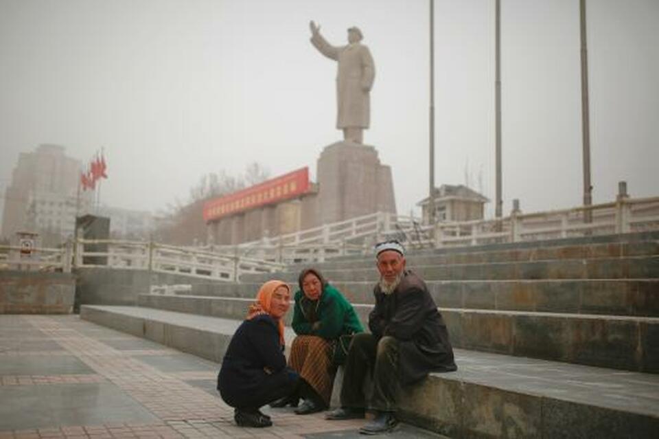 Ethnic Uighurs sit near a statue of China's late Chairman Mao Zedong in Kashgar, Xinjiang Uighur Autonomous Region, China, in this undated file photo. (Reuters Photo/Thomas Peter)