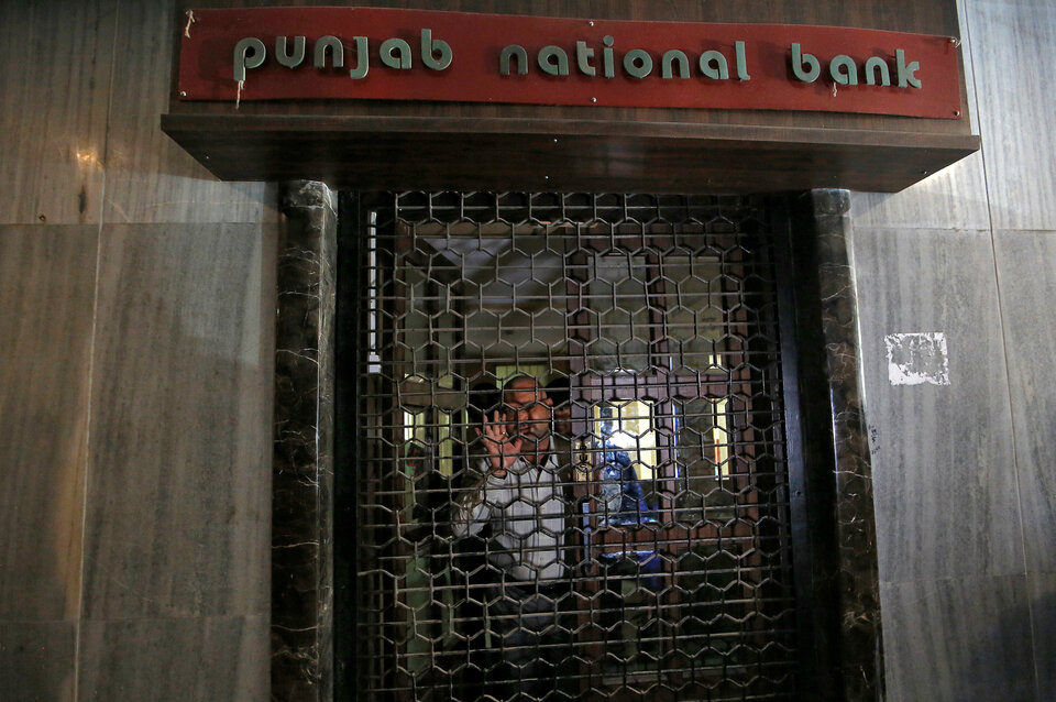 A Central Bureau of Investigation (CBI) official looks out from a closed door of a Punjab National Bank branch in Mumbai, India. (Reuters Photo/Francis Mascarenhas)