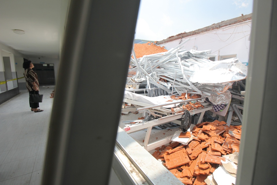 A woman is looking at a collapsed roof of the stroke center building of Dr Ramelan Hospital in Surabaya, East Java, on Sunday (18/03). The accident at the newly renovated building injured four patients. (Antara Photo/Didik Suhartono)