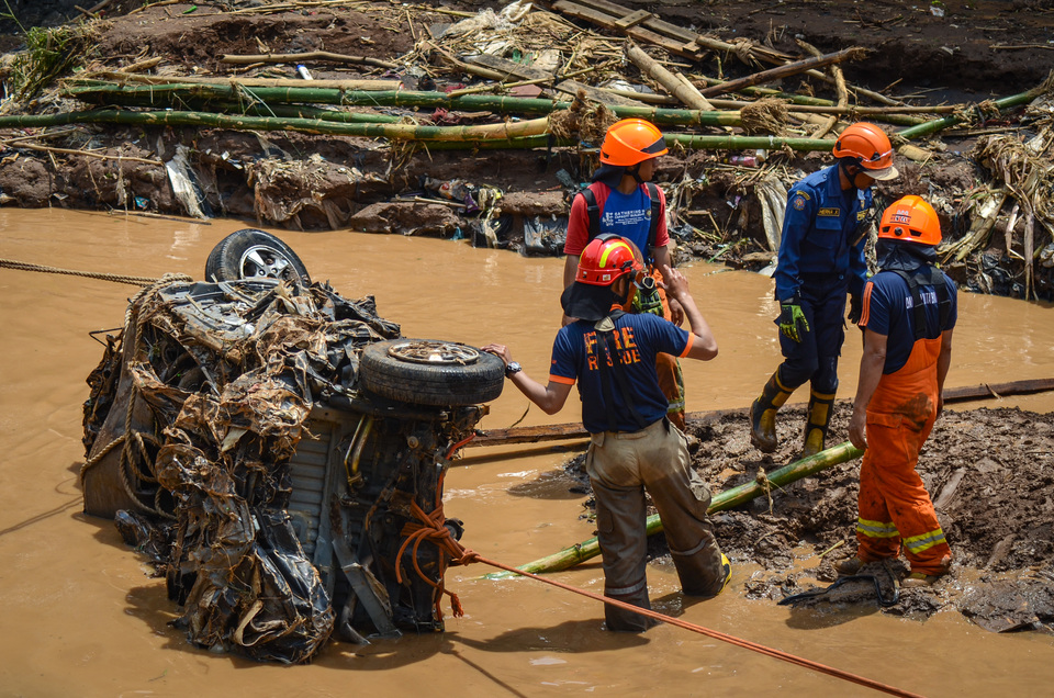 Rescue workers clear a car wreck near the Cipamokolan River in Bandung, West Java, on Wednesday (21/03). The car was carried down river due to flash floods on Tuesday afternoon. (Antara Photo/Raisan Al Farisi)

