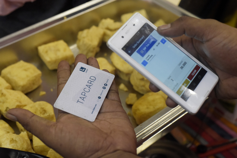 A seller uses their smartphone to process payment from customers in a mall in Depok, West Java on March 21, 2020. (Antara Photo/Andika Wahyu)