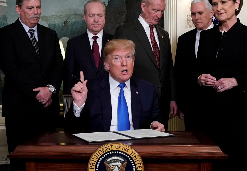US President Donald Trump, surrounded by business leaders and administration officials, prepares to sign a memorandum on intellectual property tariffs on high-tech goods from China, at the White House in Washington on March 22, 2018. (Reuters Photo/Jonathan Ernst)