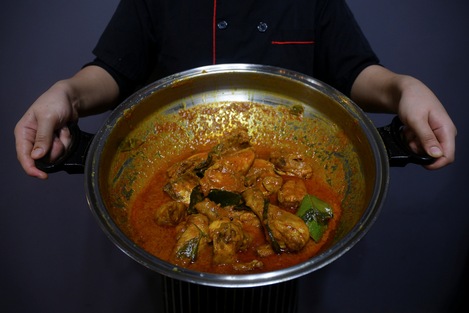 A chef holds a pot of chicken rendang for photos at a restaurant in Cyberjaya, Selangor, Malaysia. (Reuters Photo)