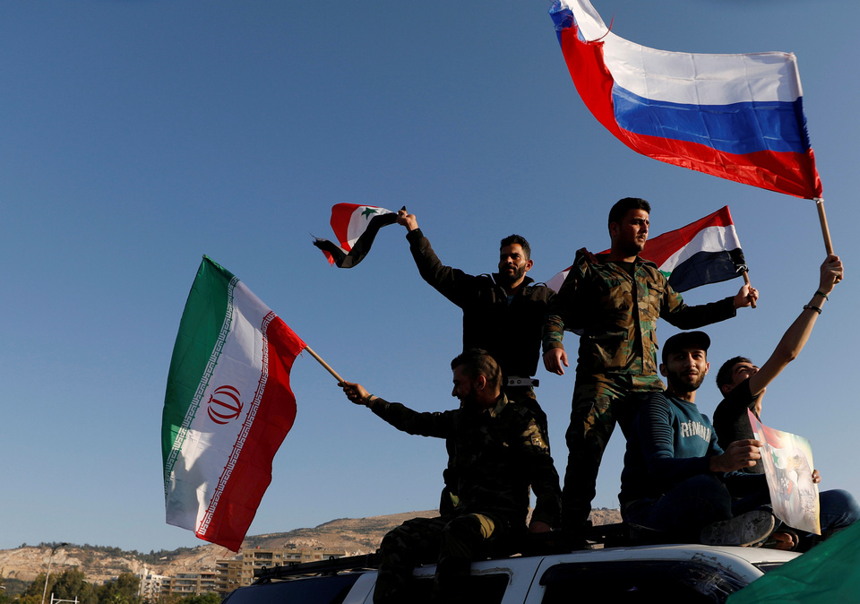 Syrians wave Iranian, Russian and Syrian flags during a protest against US-led air strikes in Damascus, Saturday (14/04).  (Reuters Photo/Omar Sanadiki)