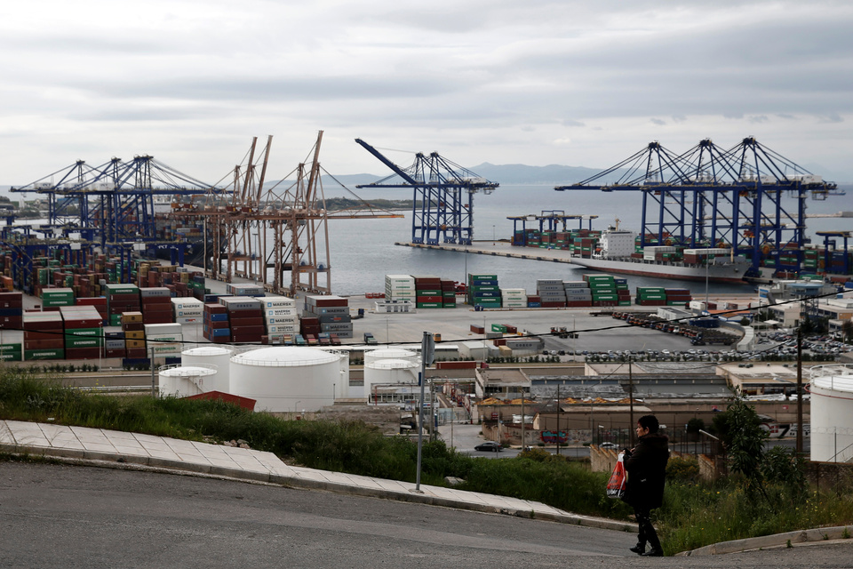 A woman makes her way as one of the three container terminals of the port of Piraeus is seen in the background at the suburb of Perama, near Athens. (Reuters Photo/Alkis Konstantinidis)