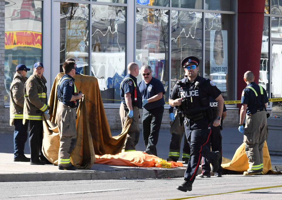 Fire fighters stand near a covered body after a van struck multiple people at a major intersection northern Toronto, Ontario, Monday (23/04). (Reuters Photo/Saul Porto)
