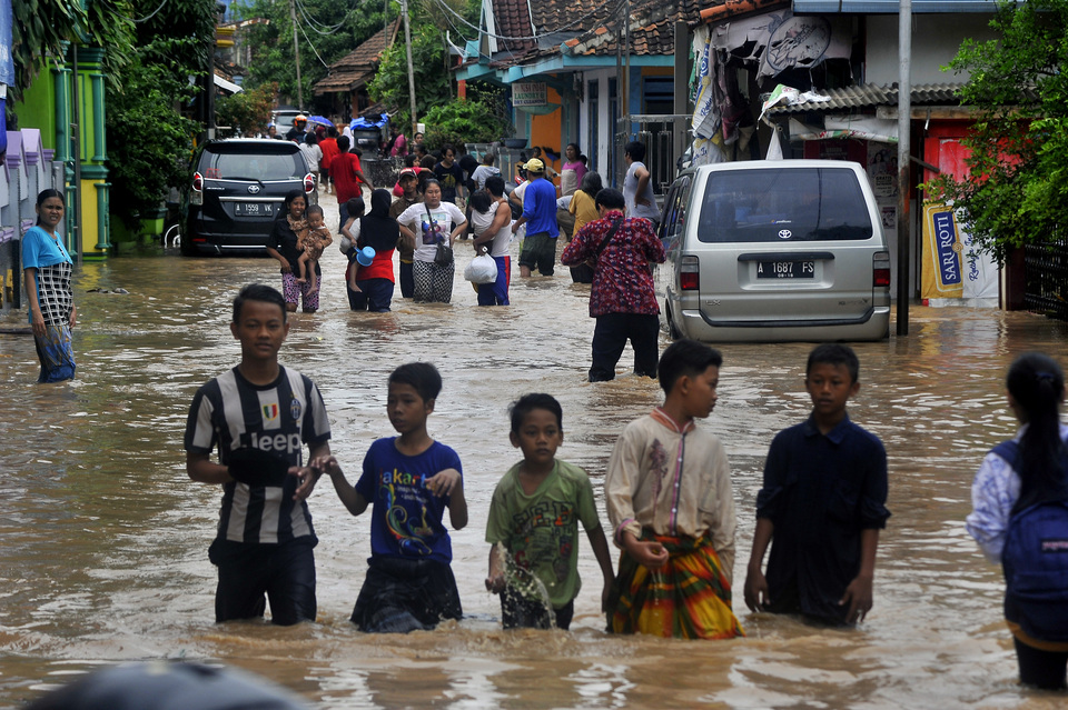 Children head to a shelter after their neighborhood in Kampung Cibeber, Cilegon, Banten, was was flooded on Wednesday (25/04). Floods in the region are caused by massive deforestation on Bukit Panenjoan and Mount Pinang, as treeless slopes can no longer hold rain water. (Antara Photo/Asep Fathulrahman)