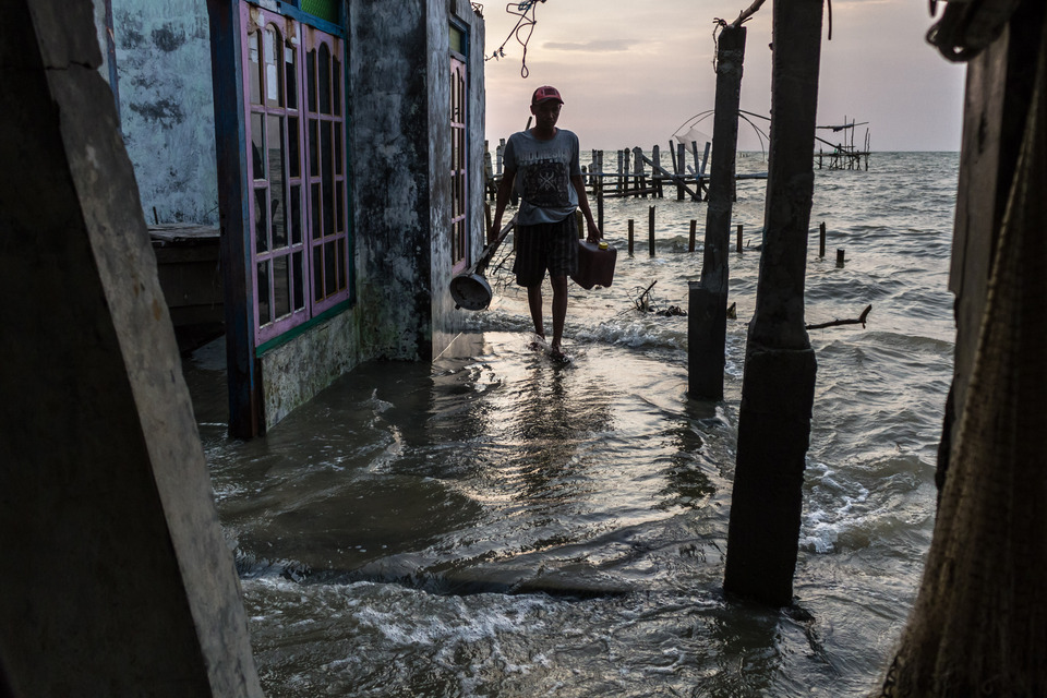 A man removes items from his flooded home in the coastal village of Bedono in Demak district, Central Java, on Tuesday (24/04). Residents have called on the government to immediately proceed with the planned Semarang-Demak Toll Road project that will be built over the sea and simultaneously serve as an embankment to halt coastal erosion that has plagued the area since 1995. (Antara Photo/Aji Styawan)