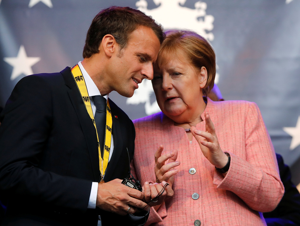 French President Emmanuel Macron talks to German Chancellor Angela Merkel after being awarded Charlemagne Prize in Aachen, Germany, Thursday (10/05). (Reuters Photo/Wolfgang Rattay)