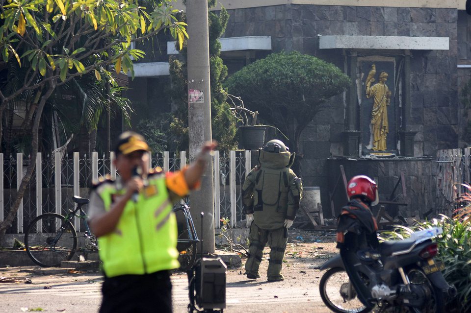 A member of the police bomb squad unit examines the site of an explosion outside the Immaculate Santa Maria Catholic Church, in Surabaya, East Java, on Sunday morning (13/05). (Antara Photo)